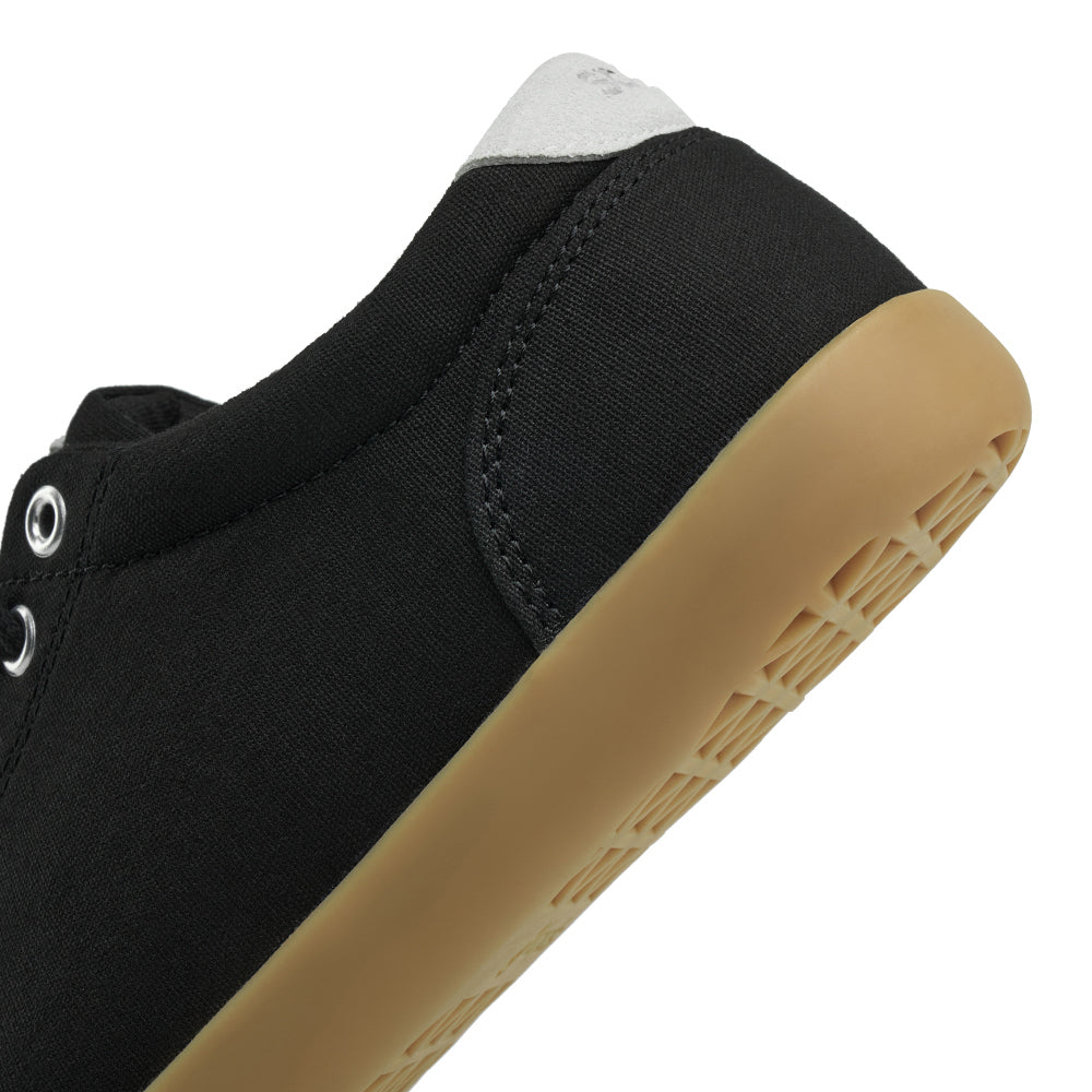 Close up view of the back half of the FREESTYLE 3 Shale, black sneaker with metalic eyelets and light grey accents on a white background