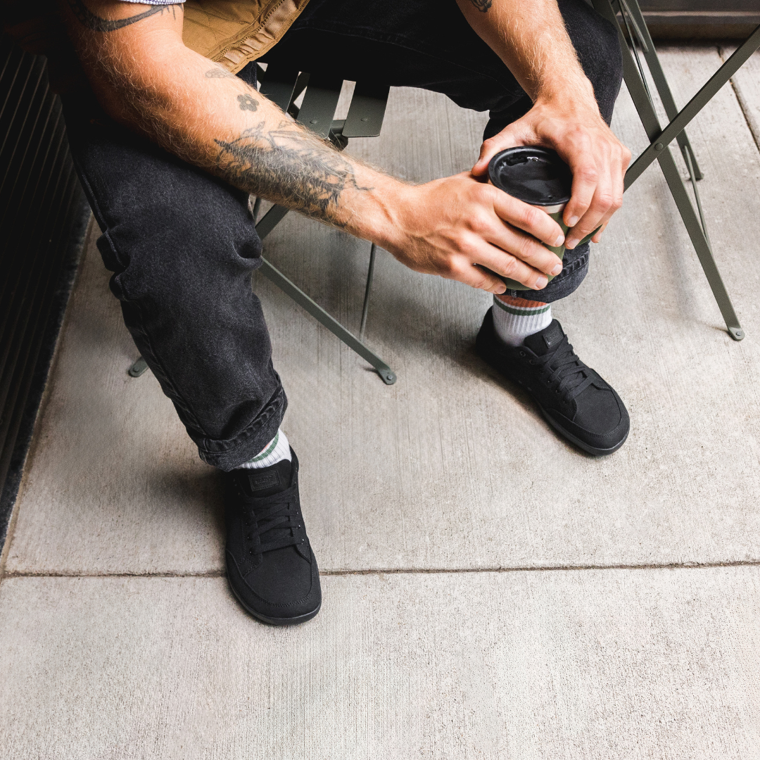 Close up picture of the FREESTYLE 3 Jet being worn by a man sitting at a coffee shop table holding a cup of coffee.