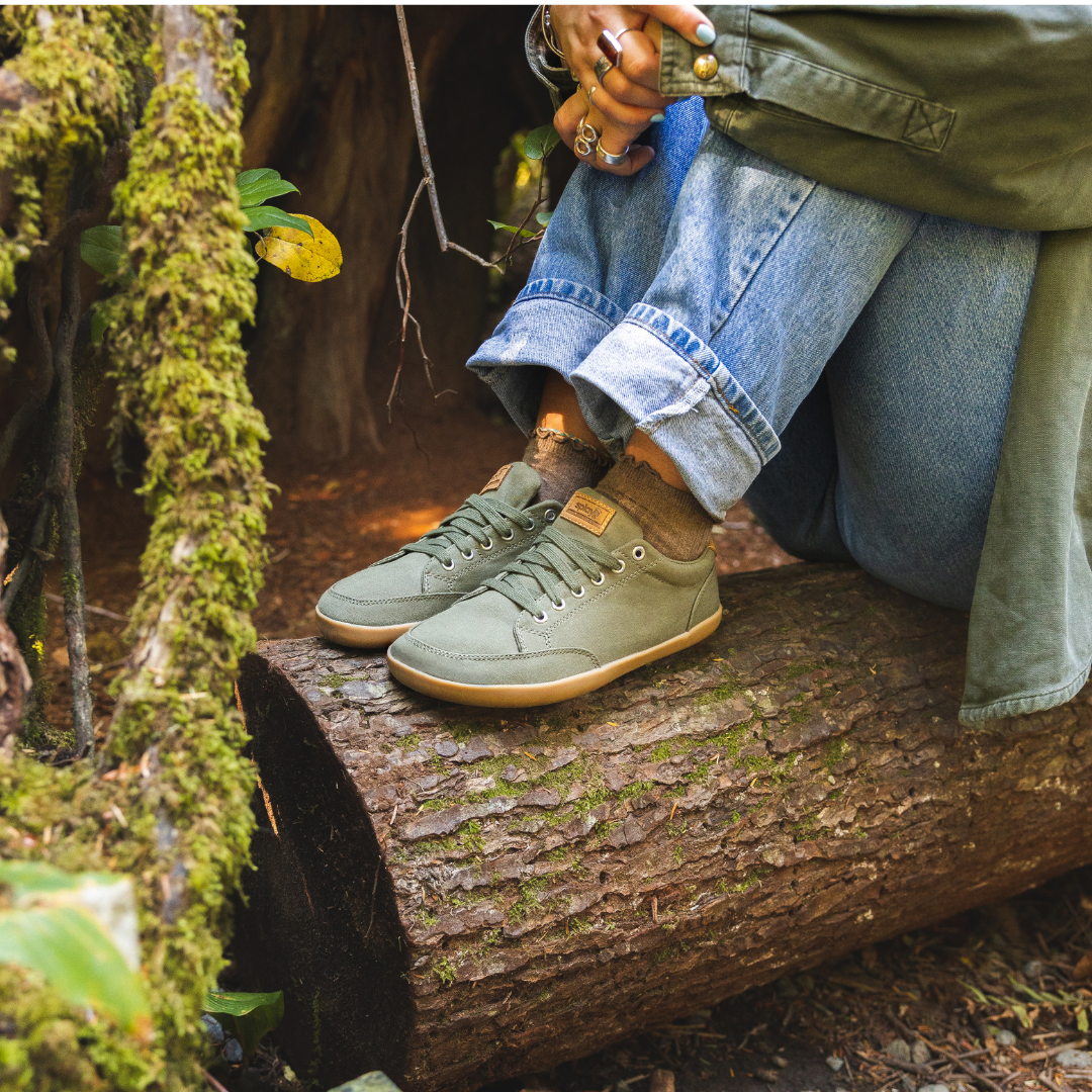 Close up picture of the FREESTYLE 3 Pine being worn by a woman sitting on a log in the forest.