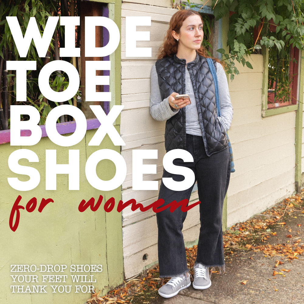 A woman leaning against a wall while standing on the street wearing a grey and white pair of Splay FREESTYLE 3 Stone barefoot shoes
