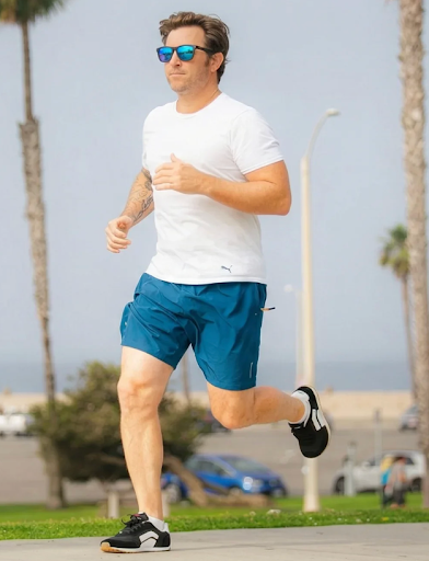 Man running on a paved road wearing Splay RUNNER V1 barefoot running shoes outdoors.