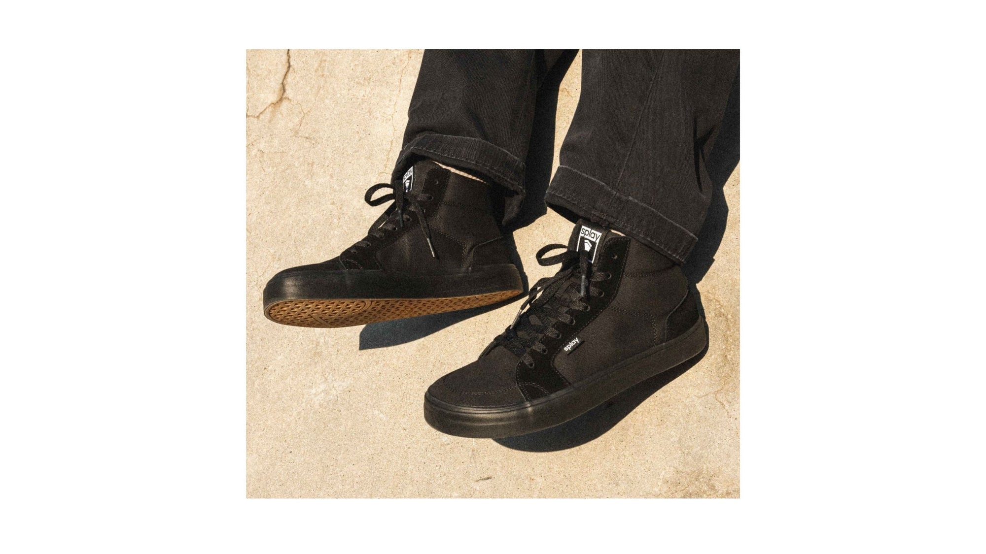 A skater wearing Splay Shoes REV HT black high-top sneakers, balancing on a skateboard at the skate park.