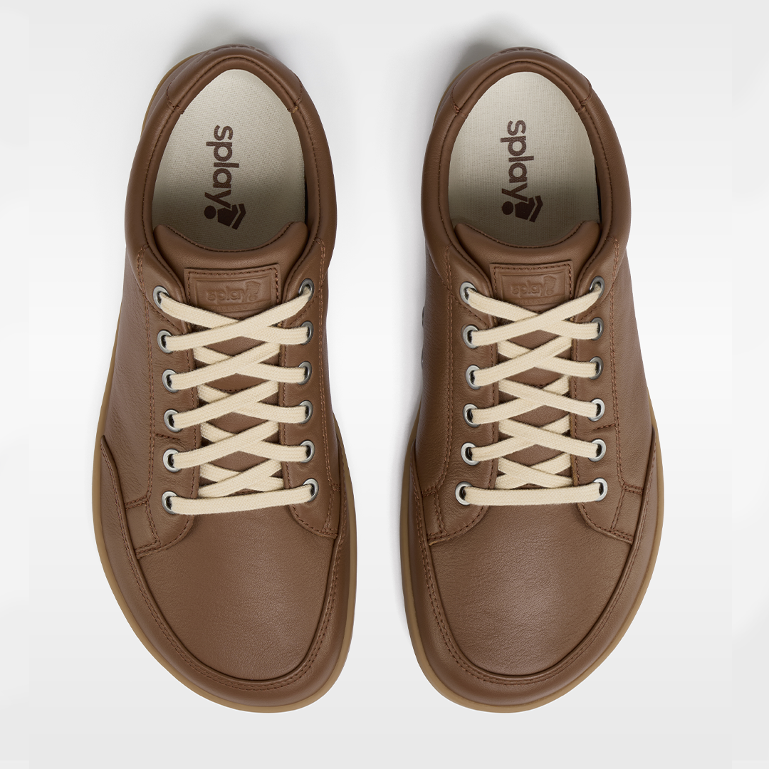 Pair of brown sneakers with white laces on a white background