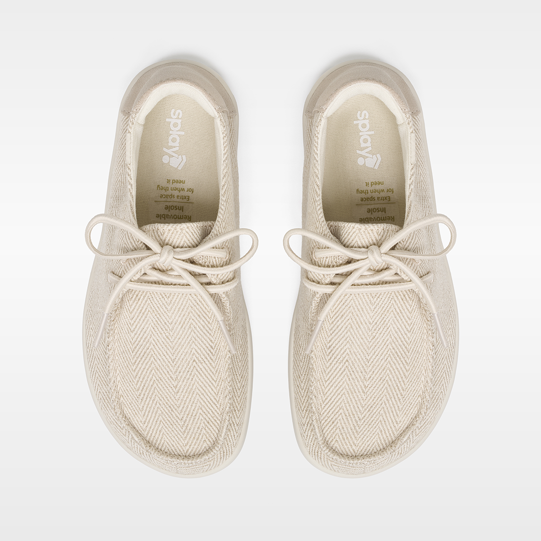 Pair of beige sneakers with white laces on a light gray background