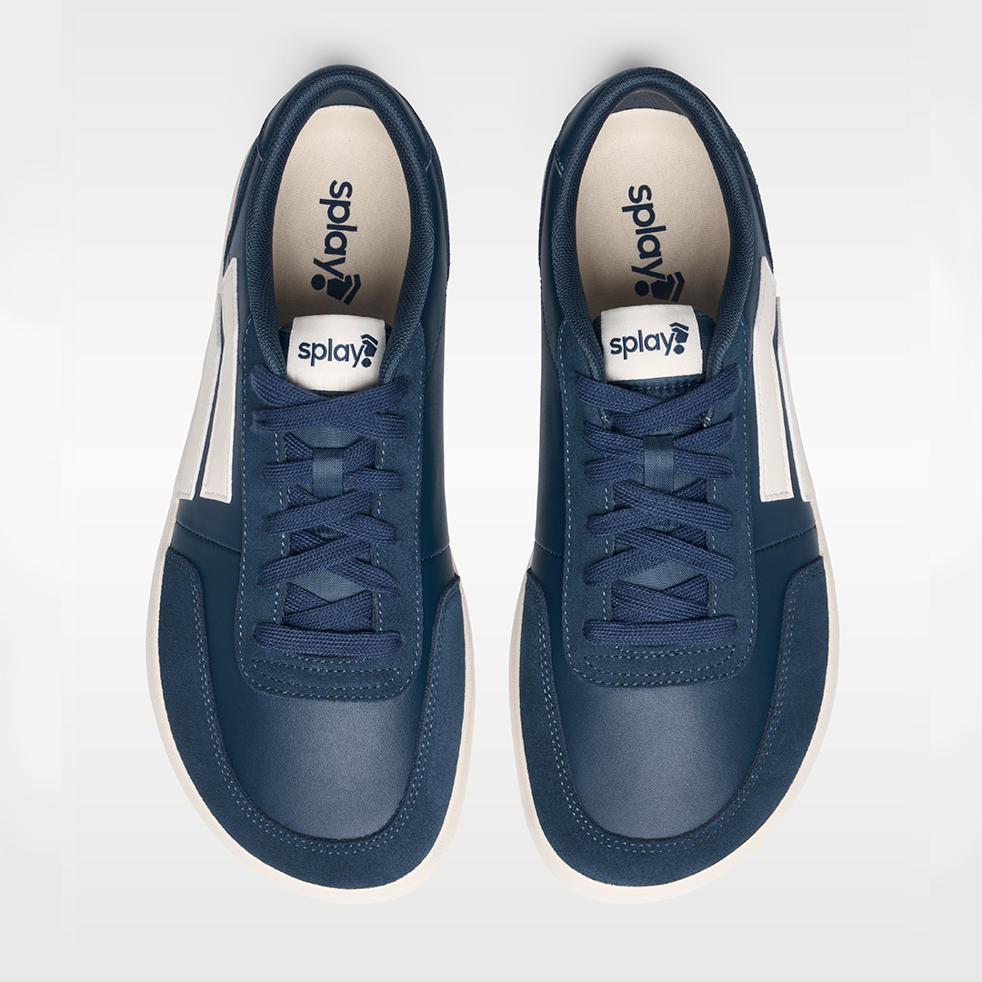 Pair of navy blue sneakers with white soles on a light gray background