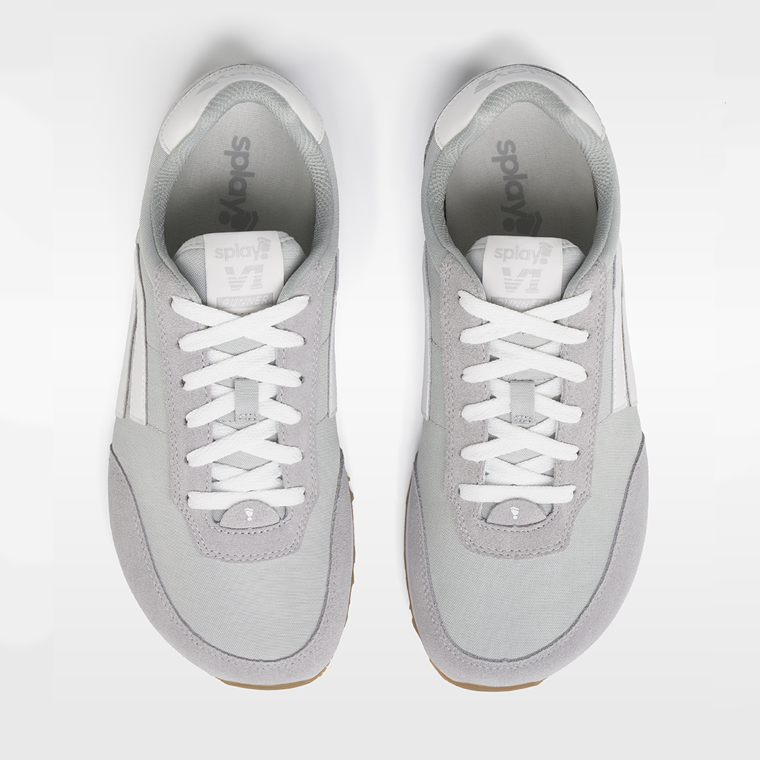 Pair of gray sneakers with white laces on a light gray background