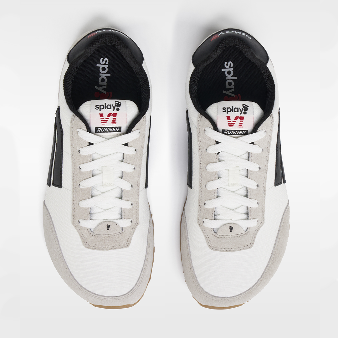 White sneakers with black soles and visible branding on a white background