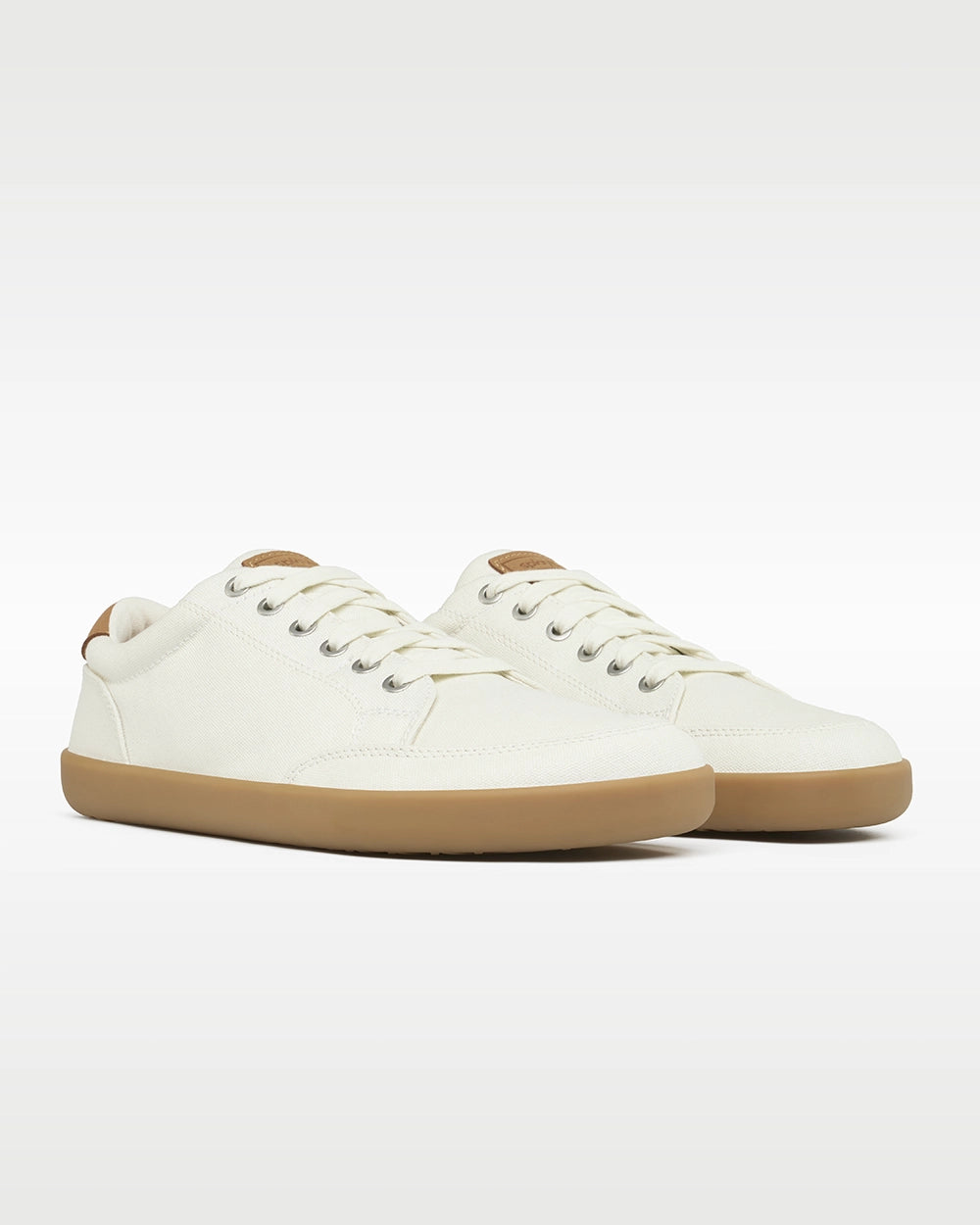 Front three-quarter view of a pair of Splay FREESTYLE Almond '26 cream canvas barefoot sneakers with gum soles.