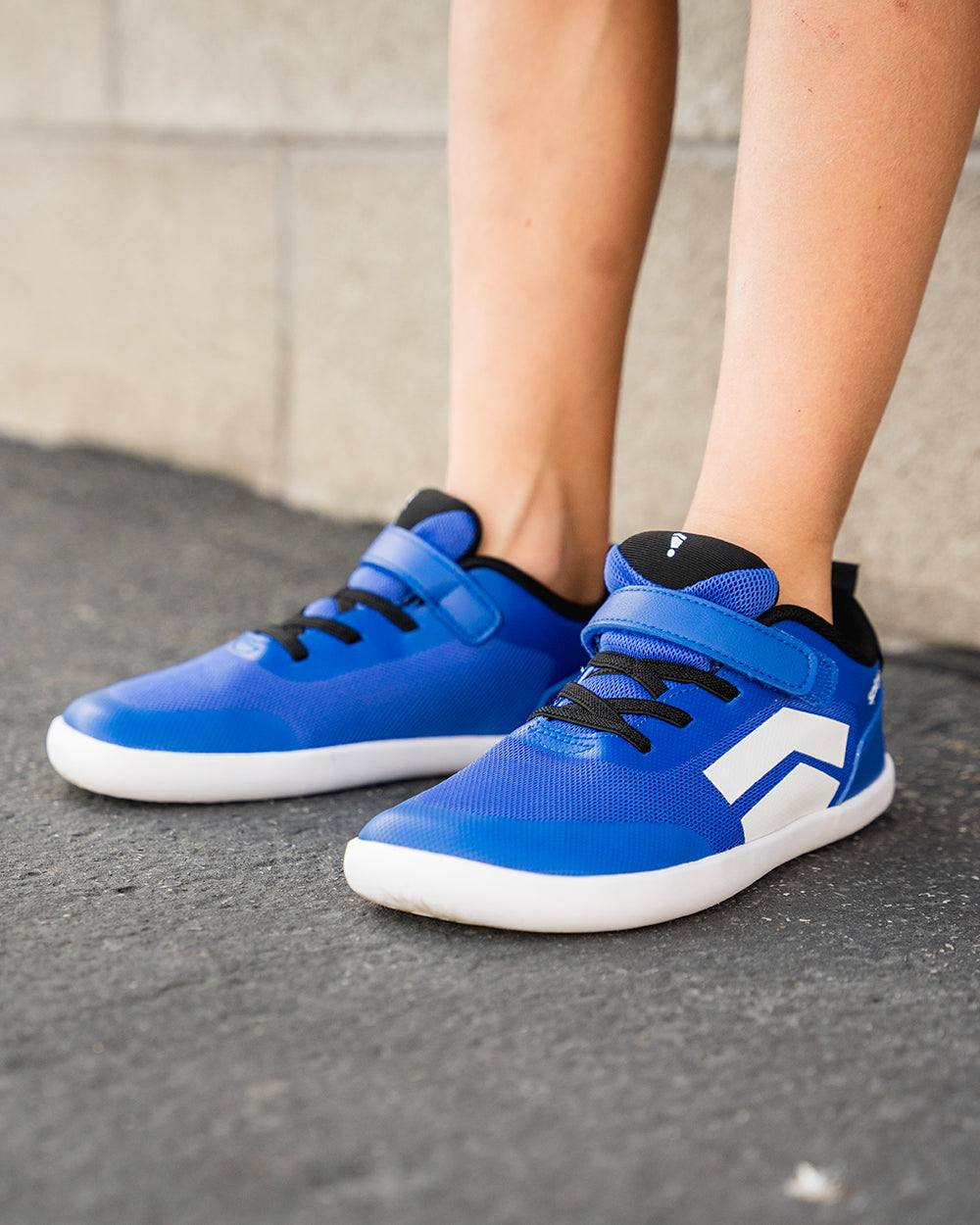 Splay Dash Kids True Blue barefoot shoes — kids' low-top sneaker with a strap and laces, lifestyle photo, the shoes shown in use outdoors