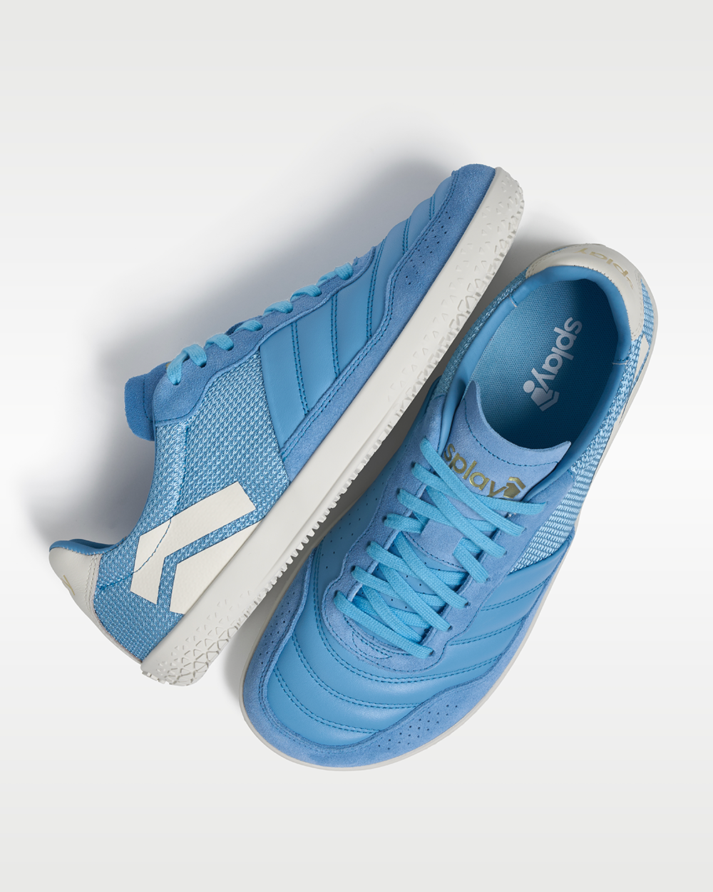 DOMINARI Caelum barefoot shoes — low-top indoor soccer shoe with a white sole, pair shot from above, one shoe tipped up to show the insole