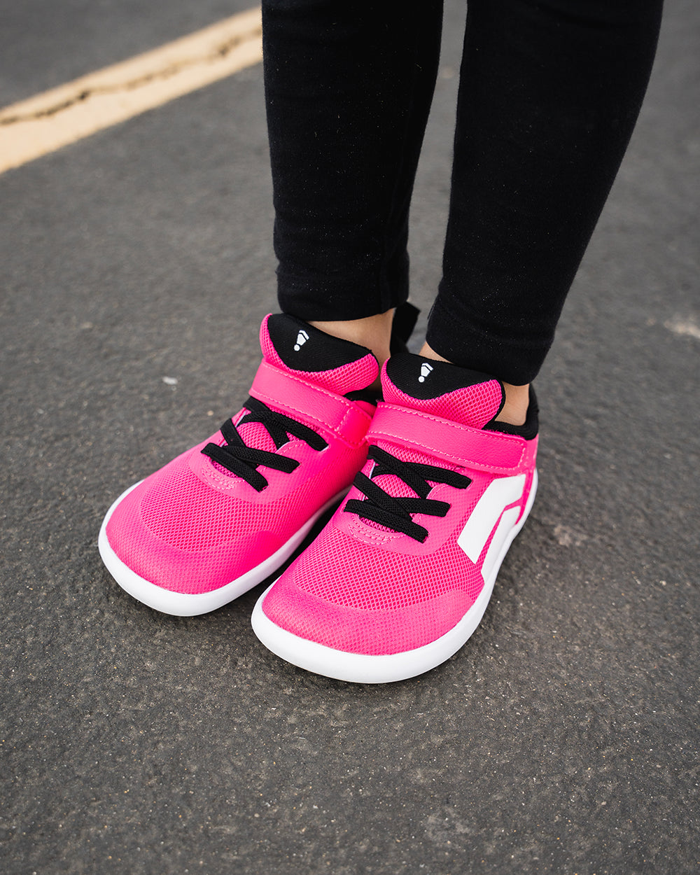 Splay Dash Kids Shock Pink barefoot shoes — kids' low-top sneaker with a strap and laces, lifestyle photo, the shoes shown in use outdoors