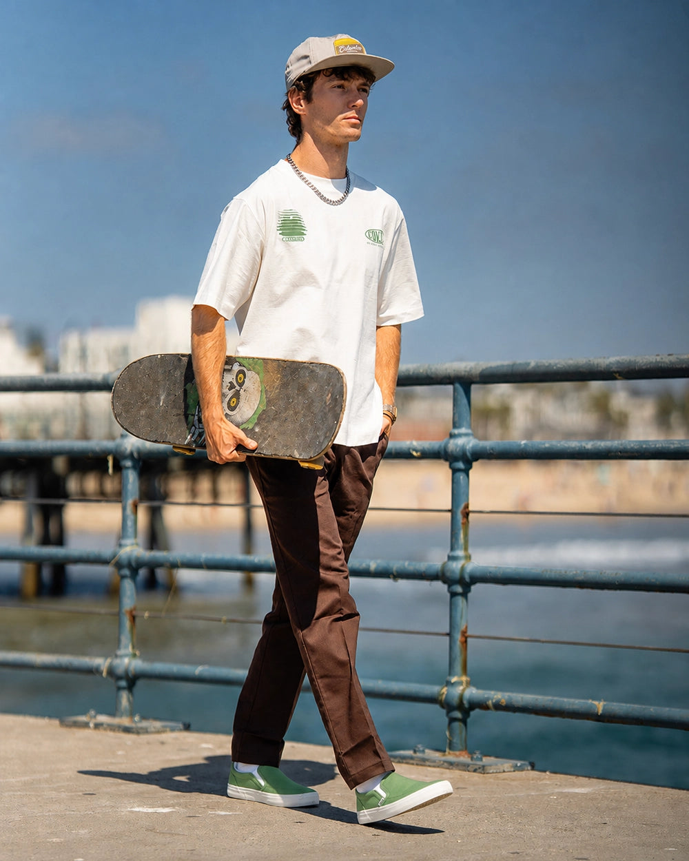 Skater walking in Splay REV SO Rio green barefoot shoes while carrying a skateboard