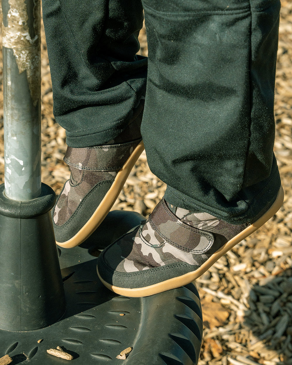 Splay Explore Wild Kids Classic Camo barefoot shoes — kids' low-top shoe with a hook-and-loop strap, lifestyle photo, the shoes shown in use outdoors