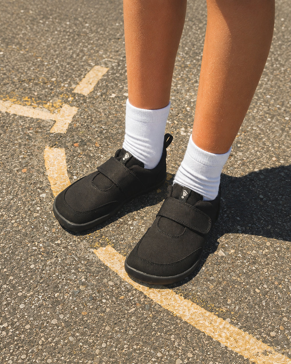 Splay Explore Wild Kids Jet barefoot shoes — kids' low-top shoe with a hook-and-loop strap, lifestyle photo, the shoes shown in use outdoors